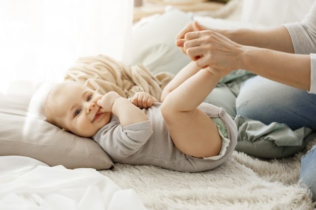 close up portrait little newborn son lying bed while playing with mother kid smiling put his fingers mouth lookin happy carefree 176420 12196